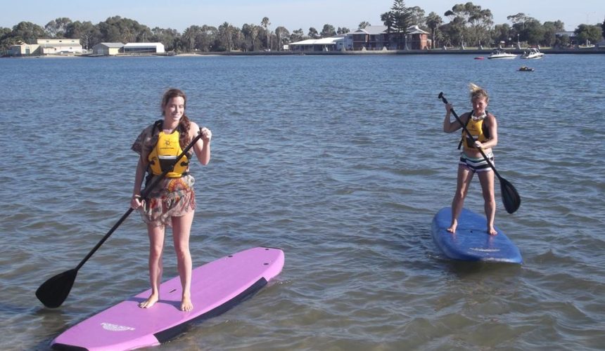 Hostel girls enjoy stand-up paddle boarding at Koombana Bay in Bunbury, an exciting outdoor activity.